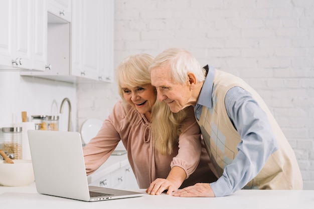 Пожилая пара с ноутбуком на кухне