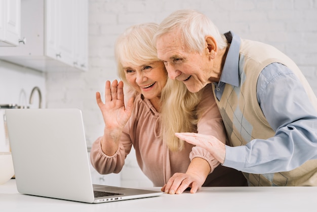 Coppie senior con il computer portatile in cucina