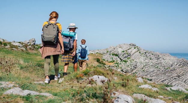 Senior couple with their adult daughter on their backs trekking