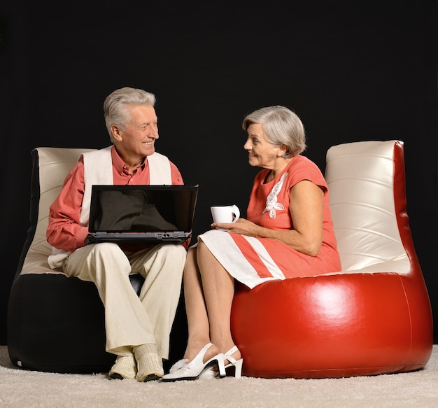 Senior couple working with notebook sitting on black background