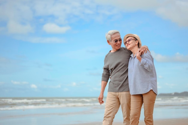 노인 부부는 일출 해변을 포용하고 행복한 은퇴라는 개념으로 생명 보험을 계획합니다.