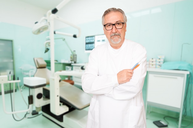 Senior dentist standing at her office