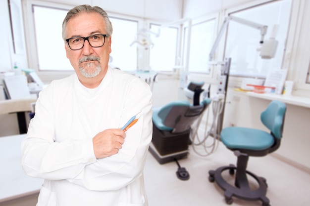 Senior dentist standing at her office