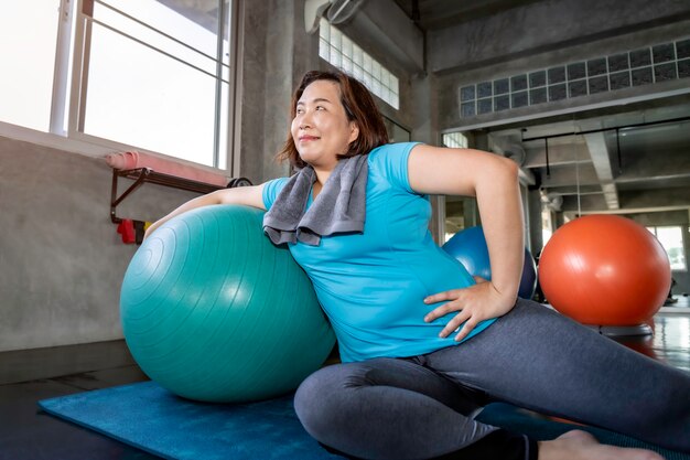 Senior dikke vrouw Aziatische doet yoga oefening op fitness gym.