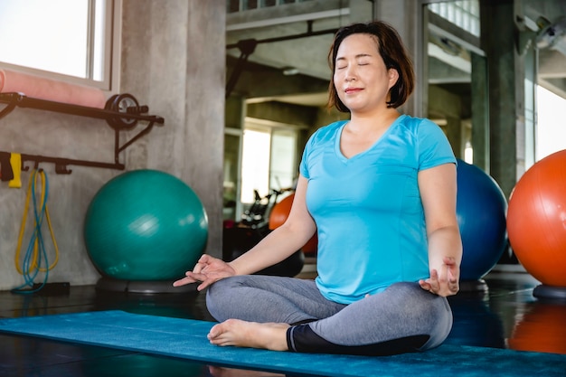 Senior dikke vrouw Aziatische doet yoga oefening op fitness gym.