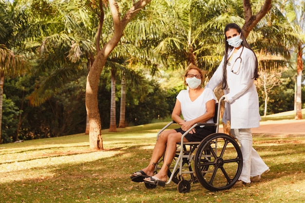 Senior donna disabile con badante nel giardino della casa di cura