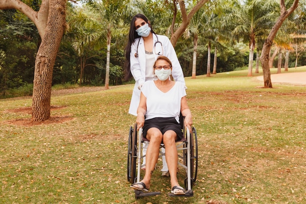 Senior disabled woman with caregiver in the garden of the nursing home