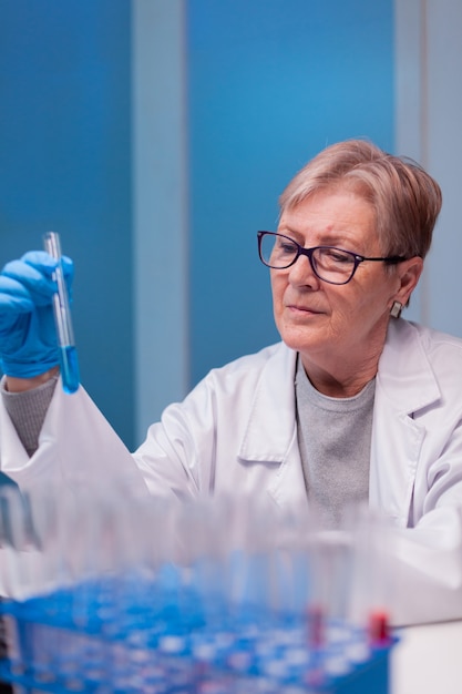 Senior doctor discovering genetic infection and analysing a test tube for medical expertise