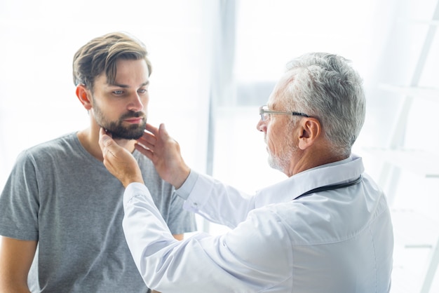 Senior doctor examining lymph nodes of patient