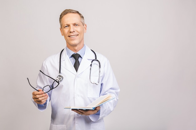 Senior doctor holding a book isolated over grey wall.