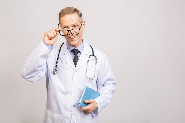 Medico senior che giudica un libro isolato sopra la parete grigia.