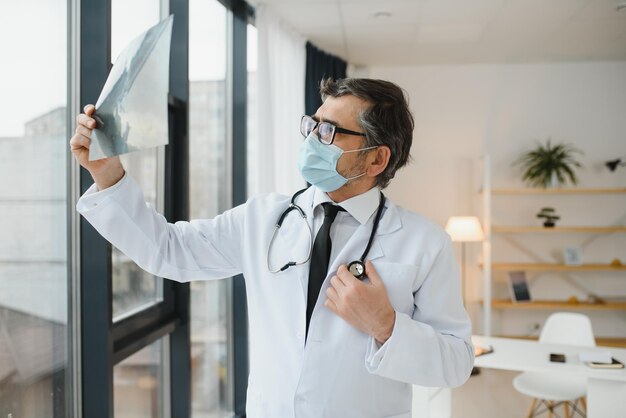 A senior doctor looking at the Xray in his office