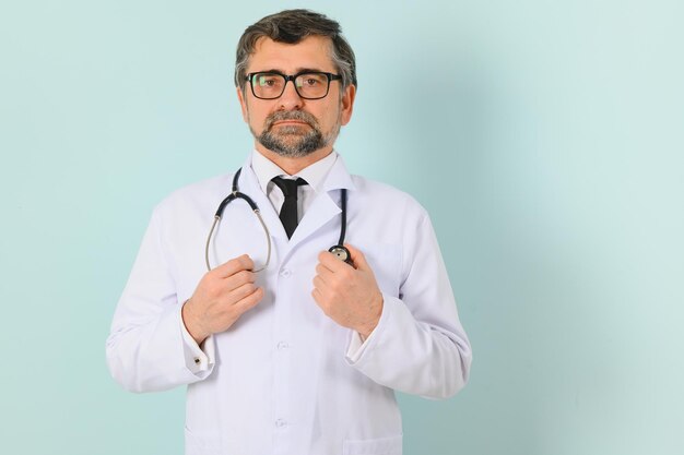 Senior doctor man wearing stethoscope and medical coat oveer blue background