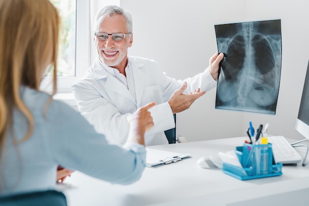 Senior doctor showing xray to his patient in medical office