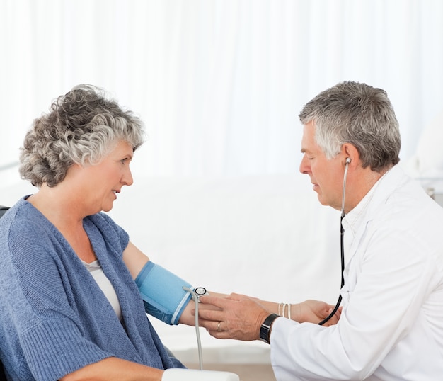 A senior doctor taking the blood pressure of his patient 