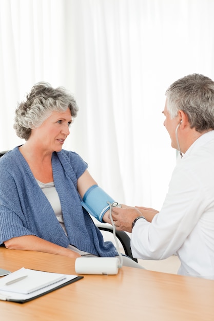 A senior doctor taking the blood pressure of his patient 