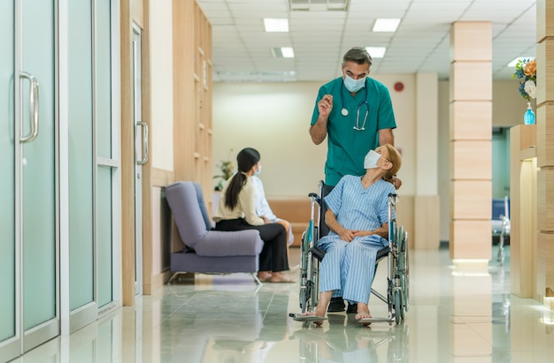 Senior doctor taking care of elderly woman patient in wheelchair