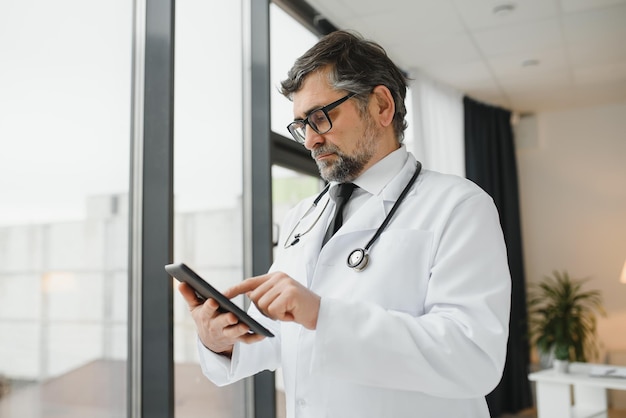 Senior doctor using his tablet computer at work