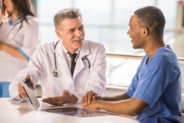 Photo senior doctor and young doctor talking and using a tablet.