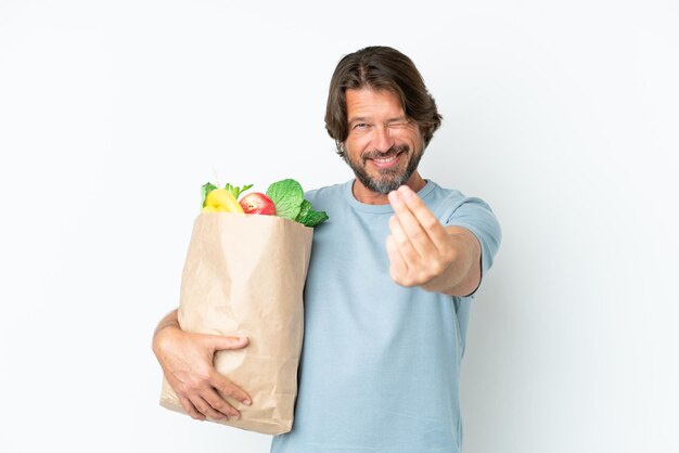 Senior dutch man holding grocery shopping bag over isolated background making money gesture