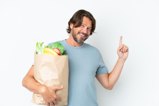 Senior dutch man holding grocery shopping bag over isolated background showing and lifting a finger in sign of the best