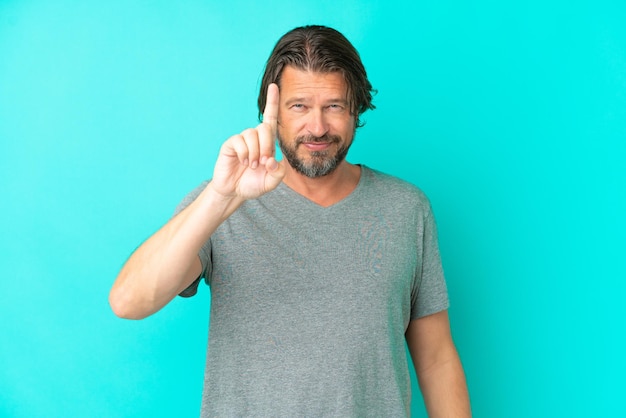 Senior dutch man isolated on blue background counting one with serious expression