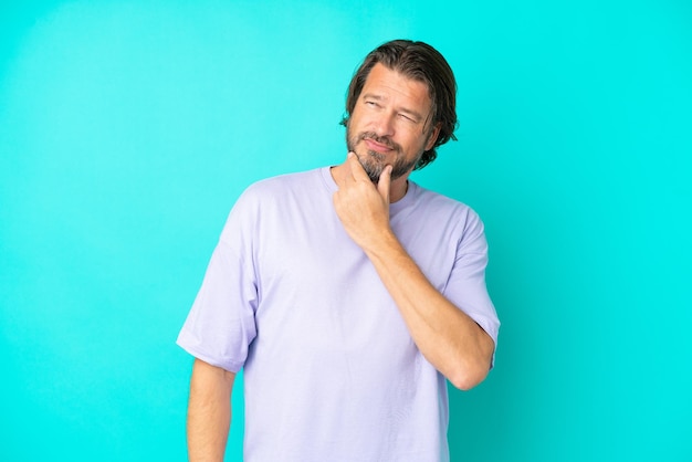 Senior dutch man isolated on blue background looking to the side and smiling