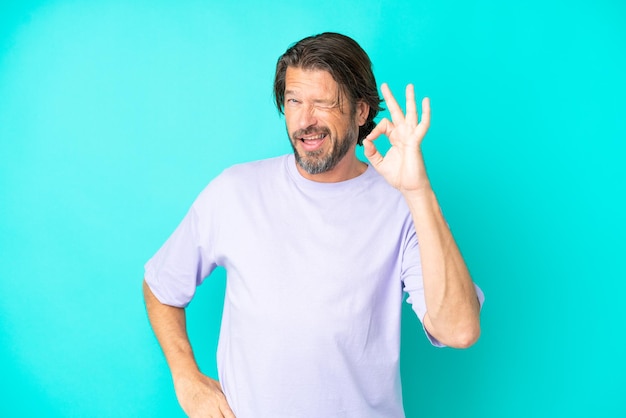 Senior dutch man isolated on blue background showing ok sign with fingers