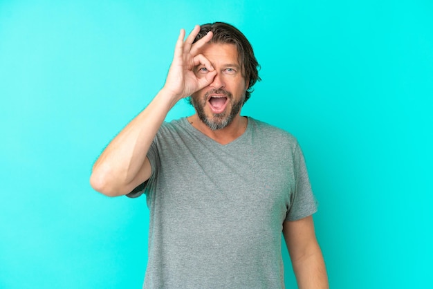 Senior dutch man isolated on blue background showing ok sign with fingers