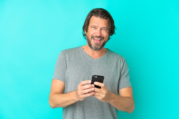 Senior dutch man isolated on blue background surprised and sending a message