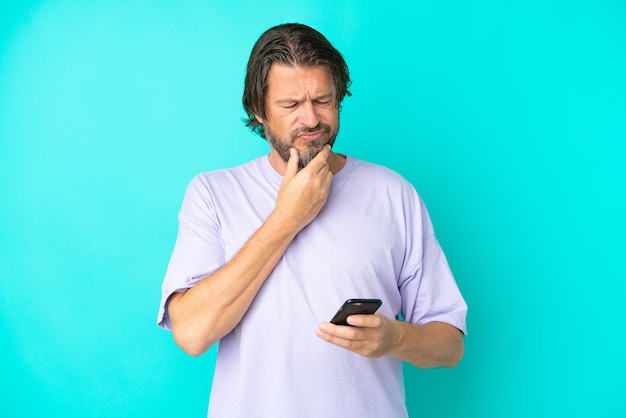 Senior dutch man isolated on blue background thinking and sending a message