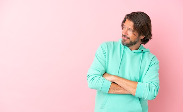 Senior dutch man isolated on pink background looking to the side