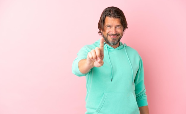Senior dutch man isolated on pink background showing and lifting a finger