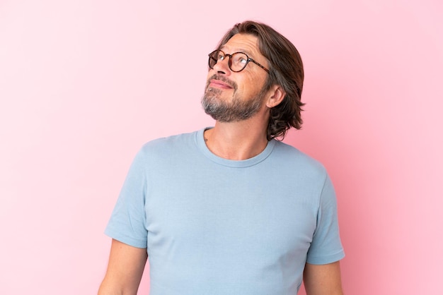 Senior dutch man isolated on pink background With glasses with happy expression