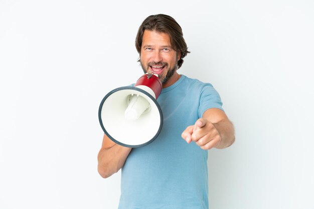 Senior dutch man isolated on white background shouting through a megaphone to announce something while pointing to the front