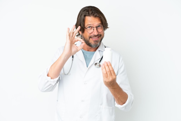 Senior dutch man isolated on white background wearing a doctor gown and holding pills