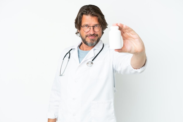 Старший голландский мужчина изолирован на белом фоне в халате врача и держит таблетки