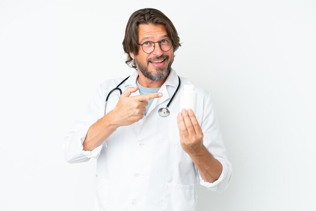 Senior dutch man isolated on white background wearing a doctor gown and holding pills