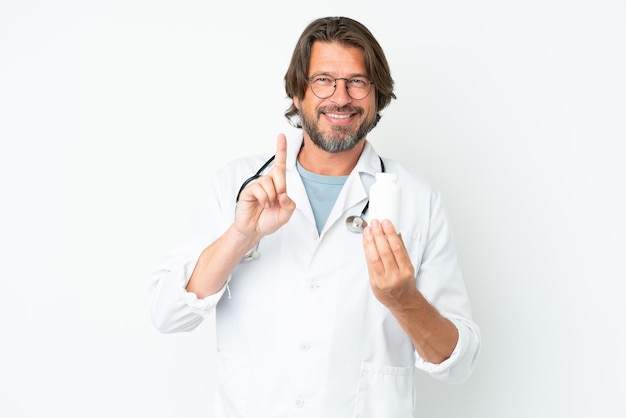 Старший голландец изолирован на белом фоне в врачебном халате и держит таблетки