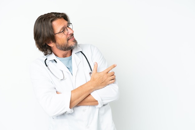 Senior dutch man isolated on white background wearing a doctor gown and pointing side