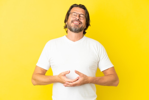 Senior dutch man isolated on yellow background laughing