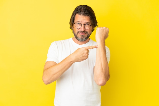 Senior dutch man isolated on yellow background making the gesture of being late