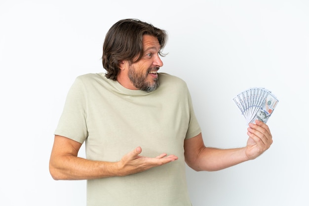 Senior dutch man taking a lot of money isolated on white background with surprise expression while looking side