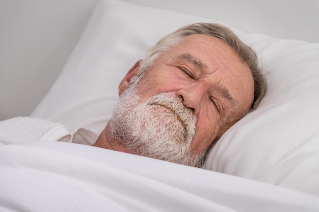 Senior elderly man sleeping with white blanket in bedroom