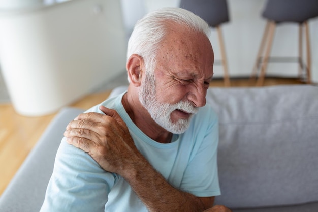 Senior elderly man touching his shoulder suffering from\
shoulder pain sciatica sedentary lifestyle concept shoulder health\
problems healthcare insurance