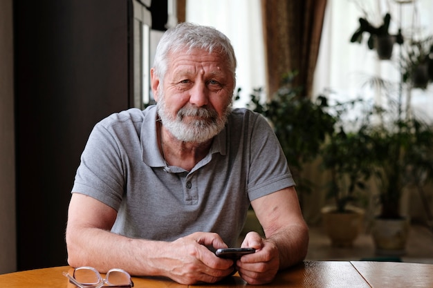 Photo senior elderly man with smart phone sitting at home