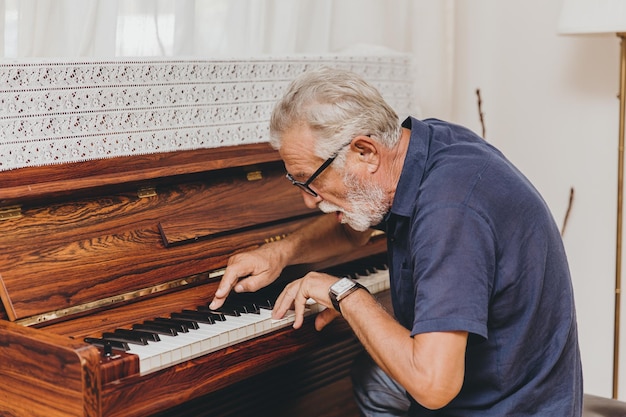 Foto il musicista anziano anziano si diverte a suonare musica felice con il pianoforte per prevenire il morbo di alzheimer