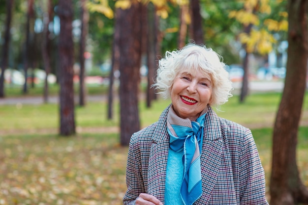 senior elegant stylish fashionable woman in coat outdoor in autumn park old age seasons fall