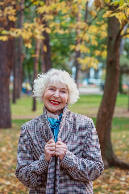 senior elegant stylish fashionable woman in coat outdoor in autumn park old age seasons fall