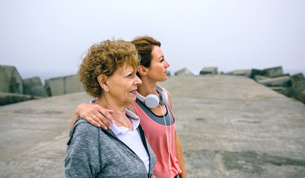 Senior en jonge sportvrouw op zoek weg door zee pier